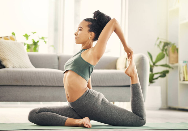 La flexibilidad es necesaria en todas partes. una joven practicando yoga en su salón - Foto, imagen