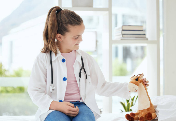 Ahora estás mejor. una niña fingiendo ser médico mientras examina a su animal de peluche en casa - Foto, imagen