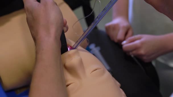 A férfi orvos egy csövet helyez a próbabábu gégéjébe egy videó gége-szkóppal. Légzőszervi intubáció oktatása a klinikán - Felvétel, videó