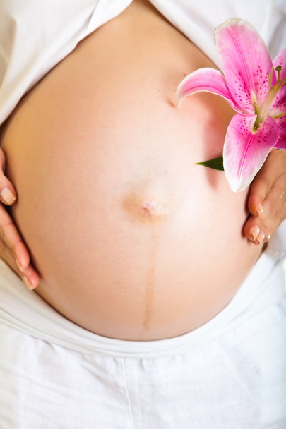 Pregnant woman holding lillies isolated on white - Valokuva, kuva