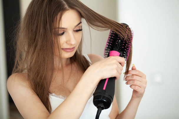 Frau mit langen Haaren und gesunder Haut trocknet sich im Badezimmer die Haare - Foto, Bild