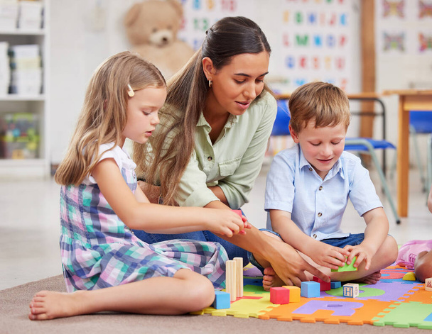 Sich im Glanz von Spielzeug und Puzzles sonnen. eine junge Frau unterrichtet eine Klasse von Vorschulkindern - Foto, Bild
