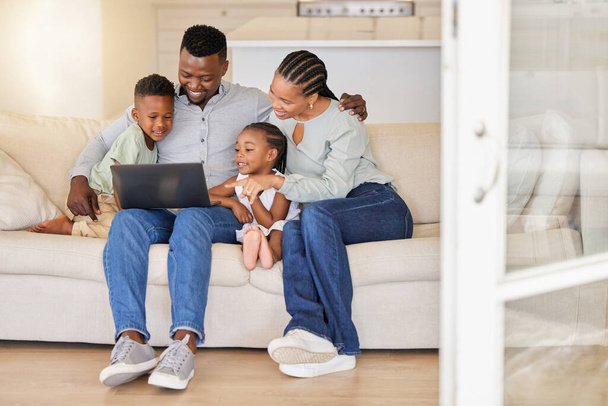 profiter au maximum des journées de détente. une jeune famille africaine regardant des films sur un ordinateur portable ensemble - Photo, image