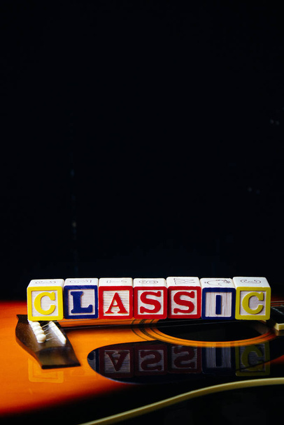 Слово или фраза Классика, сделанная из буквенных кубиков, стоящих на гитаре. - Фото, изображение
