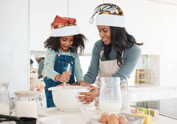 Baking with mommy. an attractive young woman and her daughter baking in the kitchen at home - Foto, Imagen