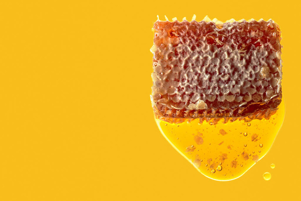 Honeycomb and flowing honey on a yellow background. Copy space. - Fotó, kép