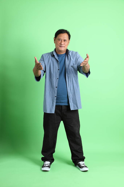 The 40s adult overweight Asian man standing on the green background. - Valokuva, kuva