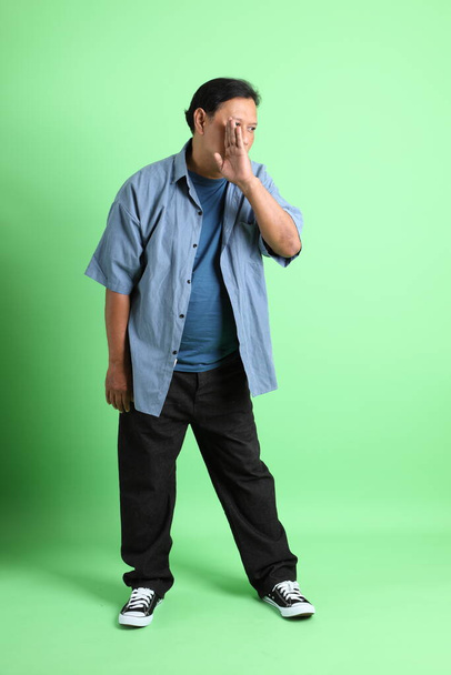 The 40s adult overweight Asian man standing on the green background. - Photo, image