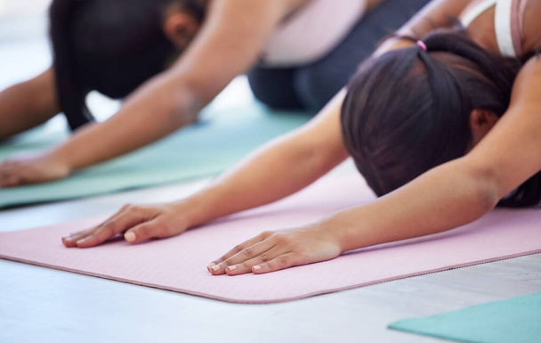 Rustig aan en focus op mindfulness. Close-up shot van een groep van sportieve jonge vrouwen doen kinderen poseren tijdens het sporten in een yoga studio - Foto, afbeelding