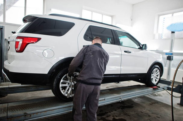 Auto mechanic sets american SUV car for diagnostics and configuration camber check in workshop of service station.. - Foto, Bild