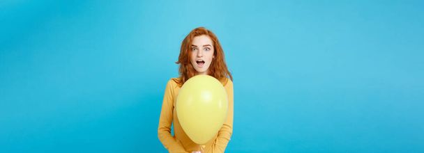 Close up Portrait happy young beautiful attractive redhair girl smiling with colorful party balloon. Blue Pastel Background. - Фото, зображення