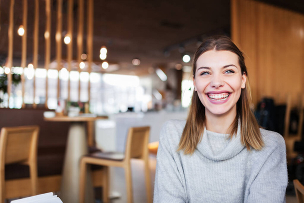 Portrait of a cute girl with beautiful smile in a cafe. - 写真・画像