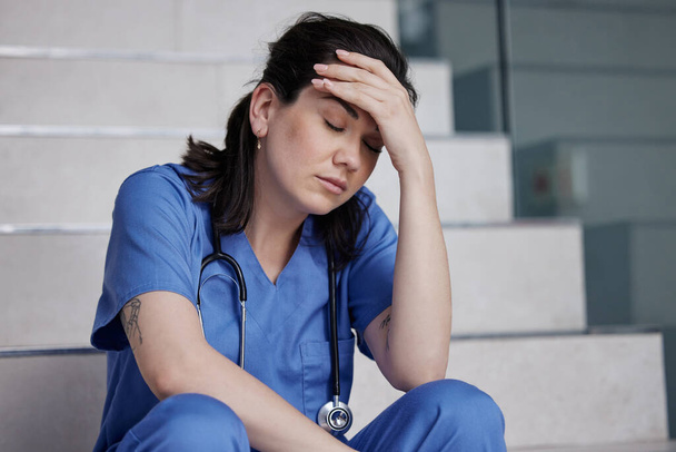 Довгі години платять. молода жінка-лікар, яка виглядає втомленою під час роботи в сучасній лікарні
 - Фото, зображення