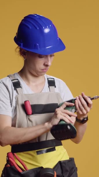 Dikey video: Dekonstrüksiyon ve onarım için elektrikli matkap veya aletle çalışan kadın inşaatçı. Yenileme için çivi tabancası kullanmak, alışılmadık. - Video, Çekim