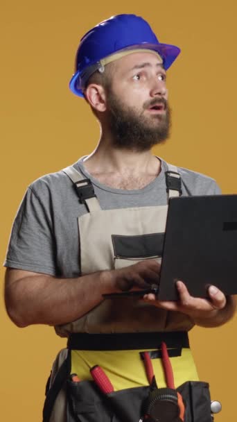 Vidéo verticale : Portrait d'un bricoleur utilisant un ordinateur portable pour trouver l'inspiration de la construction et travailler sur le schéma ou le plan de rénovation. Naviguer sur Internet sur PC pour faire des processus de mesure et d'ingénierie en studio - Séquence, vidéo