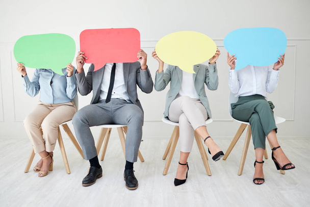 Make sure they hear you. a group of unrecognizable businesspeople holding speech bubbles while sitting in line against a grey background - Photo, Image