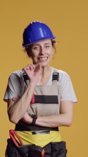 Vertikales Video: Porträt eines Bauarbeiters, der Schweigezeichen macht, Werbung für Schweigen und Privatsphäre-Geste. Konstrukteurin hält sich bedeckt und zeigt vertrauliches Symbol über Studiohintergrund. - Filmmaterial, Video