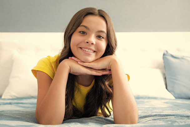 Genç kız yatakta hayal kuruyor, çocuk hayalleri kuruyor. Olumlu ve gülümseyen duygular - Fotoğraf, Görsel