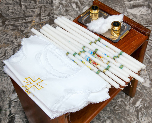 Θρησκευτικά σύμβολα της Αγίας Χριστιανικής Καθολικής βάπτισης. Λευκό πουκάμισο, κεριά και λαδόκολλα. - Φωτογραφία, εικόνα