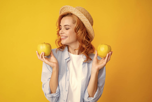 Portret szczęśliwej młodej dziewczyny trzymającej zielone jabłko na żółtym tle. Szczęśliwa biała kobieta trzyma świeże zielone jabłko i uśmiecha się. Zdrowa żywność - Zdjęcie, obraz