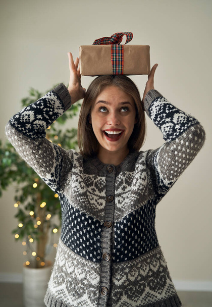 Mujer caucásica sosteniendo regalo de Navidad sobre su cabeza  - Foto, Imagen