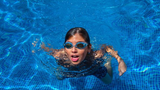 Retrato de un niño en la piscina exterior. Adolescente con gafas de natación. Vacaciones de verano en el hotel o clases de natación al aire libre. concepto de estilo de vida saludable - Foto, imagen