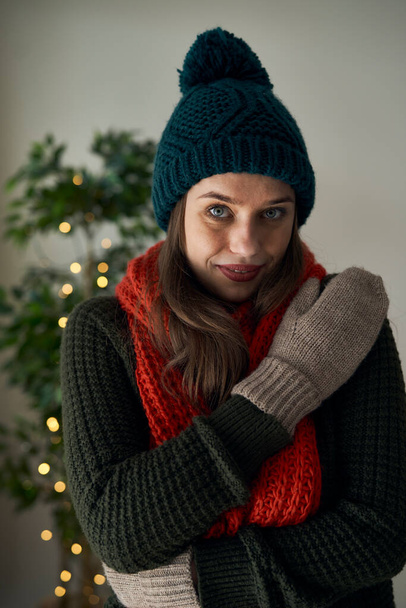 Кавказька жінка в капелюшних рукавицях і шарфі вдома під час Різдва. - Фото, зображення