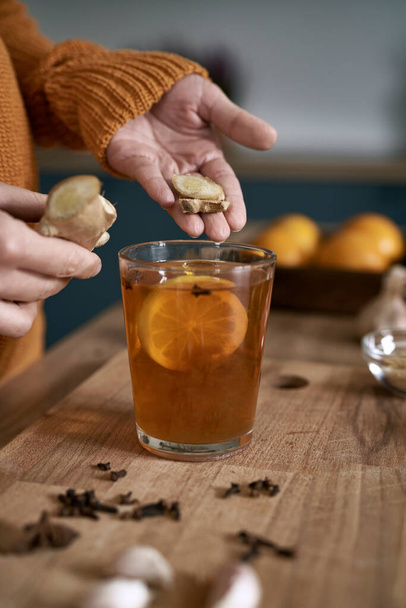 Close up of woman's hands adding ginger to the tea  - Foto, immagini