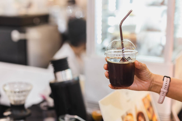 Kundin hält Eiskaffee in Plastikglas mit Stroh - Foto, Bild
