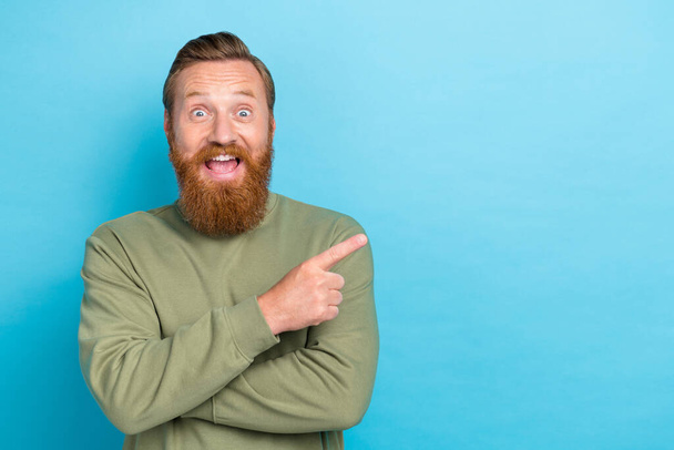 Photo of speechless staring crazy man with red hairstyle dressed khaki long sleeve directing empty space isolated on teal color background. - Fotografie, Obrázek