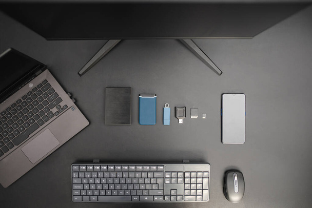 Work station for a content creator or digital worker with laptop, keyboard, memory cards, external hard drive and usb. Back background. Minimalist concept. Top view - Photo, Image