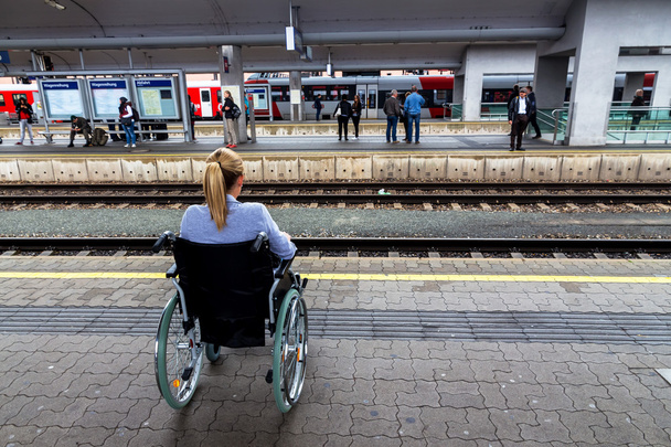 woman sitting in a wheelchair on a train station - Foto, Bild