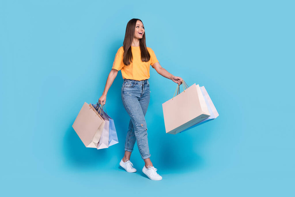 Photo of cheerful lady trendy clothes outfit hold bags enjoy shopping buy new collection look empty space isolated on blue color background. - Foto, immagini