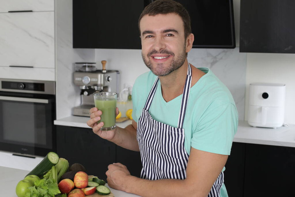 portrait de beau jeune homme avec un verre de jus de légumes frais à la maison - Photo, image