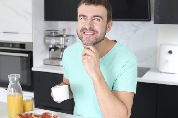 portrait of handsome young man with coffee and sandwiches for breakfast at home - Fotografie, Obrázek