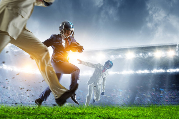 Businessman playing american football on the field. Mixed media - 写真・画像