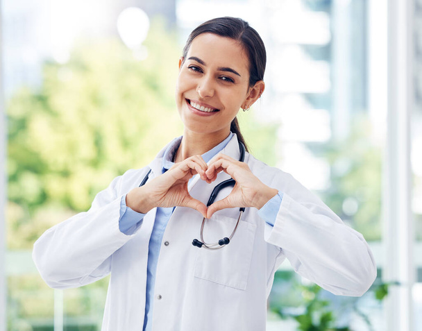 İyi bir doktor olmak inanılmaz derecede merhametli olmak demektir. Hastanede elleriyle kalp şekli yapan genç bir doktorun portresi. - Fotoğraf, Görsel