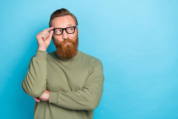 Photo portrait of attractive young guy touch eyewear look skeptical empty space wear khaki clothes isolated on cyan color background. - 写真・画像