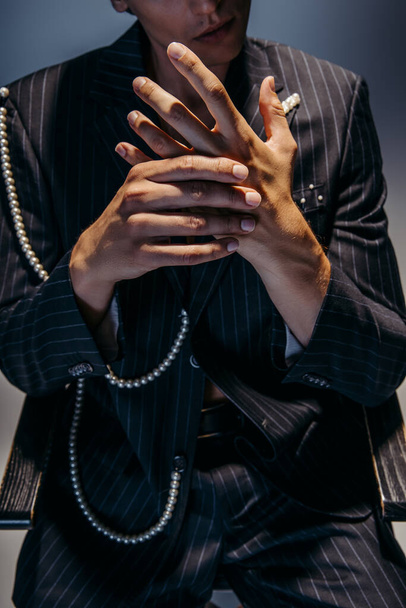 cropped view of stylish man in trendy suit with pearl chain gesturing on dark gray  - Fotó, kép