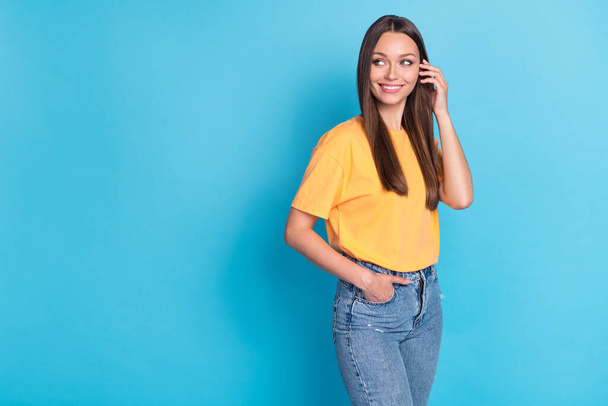 Photo of lovely cheery lady wear yellow clothes arm touch hair interested look empty space isolated on blue color background. - Foto, imagen