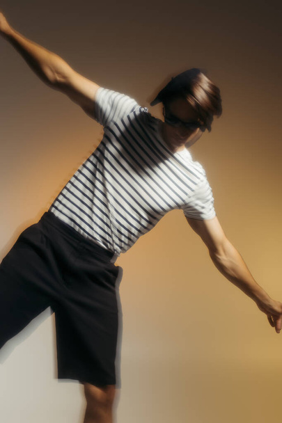 Motion blur of man in striped t-shirt posing on yellow background  - Photo, Image