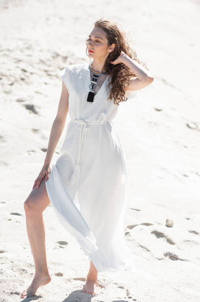 красива молода жінка в білій сукні позує на пляжі
 - Фото, зображення