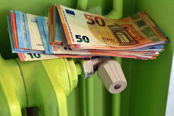 Koncepcja wydatków na ogrzewanie z paczką banknotów euro na kaloryferze - Zdjęcie, obraz