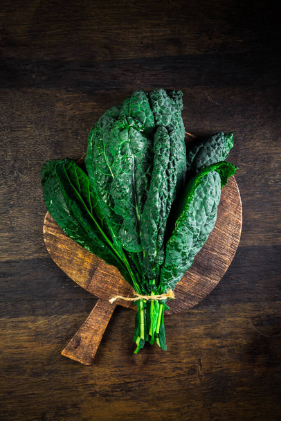 Palm kale, black cabbage - Cavolo nero black curly kale. Nero di Toscana (Brassica oleracea) on cutting board - 写真・画像