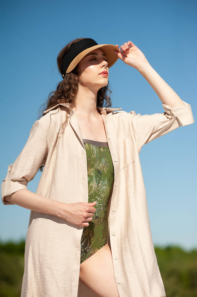 beautiful young woman in a white dress and hat posing on a background of blue sky - Foto, Imagem