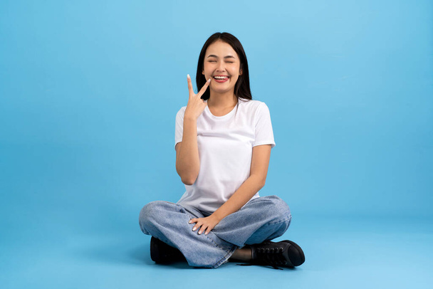 Beautiful girl sitting doing various poses On a blue background, sitting, smiling, happy, relaxing, excited, having fun. - Photo, Image