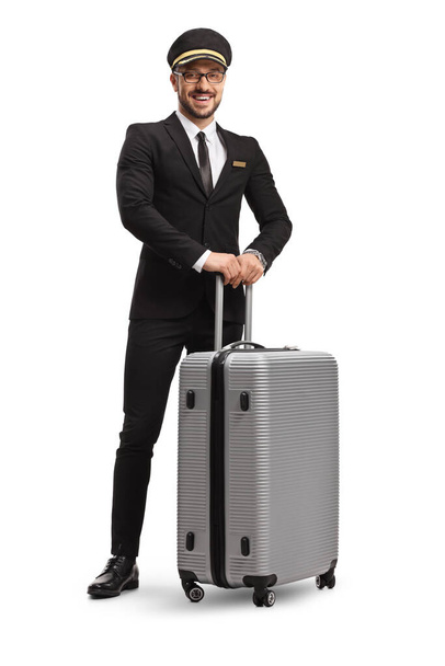Full length portrait of a pilot in a uniform standing with a suitcase isolated on white background - Photo, Image
