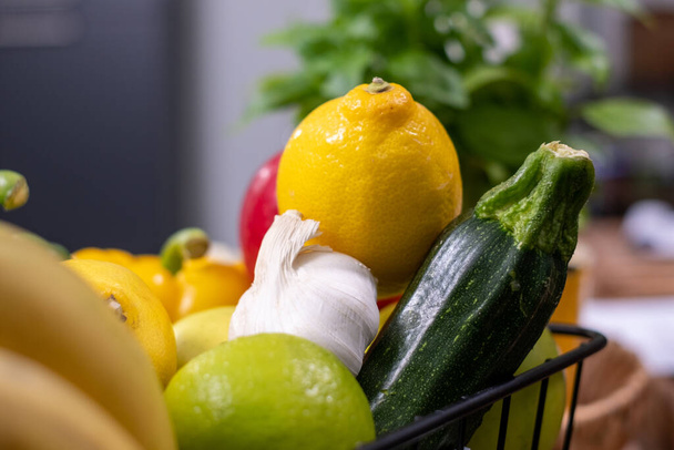 zwart metalen mandje met kleurrijke groenten en fruit en wazige keuken op achtergrond. keukenachtergrond. Reclame voor gezonde voeding, poster - Foto, afbeelding