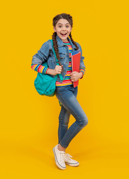 Surprised girl back to school. Teenage girl holding school books yellow background. School education. - Foto, Bild