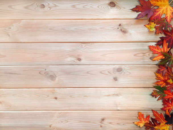 Variegated fallen leaves on wooden background. Thematic content. Flat lay. Copyspace for text or inscription. Lots of maple leaves on right on light tabletop. Top view. Layout. Concept of autumn holidays and festivals. Empty space on the left. - Photo, Image